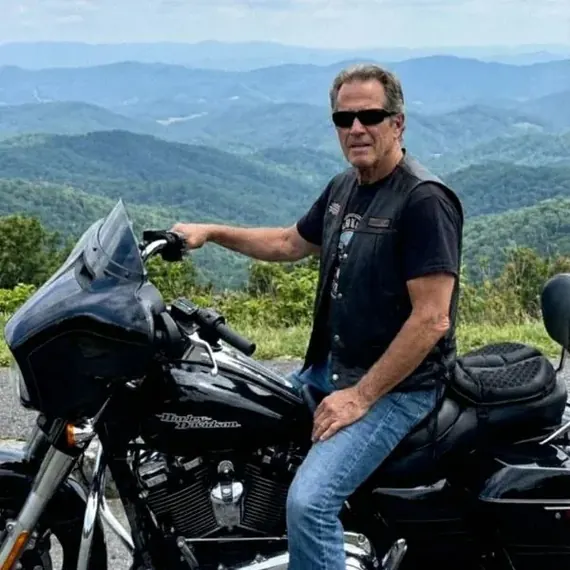 Gordon L. on his Harley-Davidson, overlooking the mountains